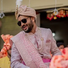 A candid shot of the groom, Nayan, smiling during his baraat. His sunglasses and joyful expression perfectly capture the fun and excitement of the moment.