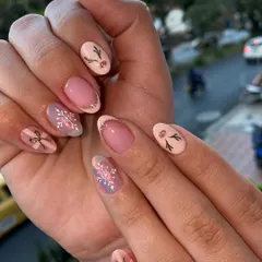 A cute and subtle take on holiday nails. This set features delicate, hand-painted snowflakes, bows, and reindeer antlers on a soft pink base.