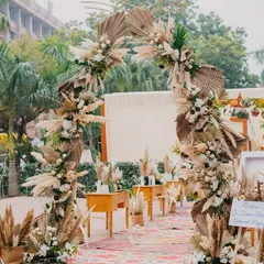 The entrance to a 'Farmer's Market' themed event. The decor uses pampas grass, dried palms, and a rustic welcome sign to create a chic, bohemian vibe right from the start.