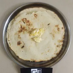 A soft Makai Rotla (maize flour flatbread) topped with a dollop of butter. This gluten-free bread is a healthy and traditional choice, especially popular in the winter.