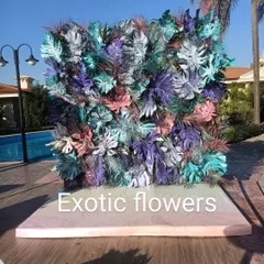 A modern art installation for a poolside party. This photo wall is made from monstera leaves painted in cool shades of blue, purple, and pink, creating a trendy and unique backdrop.