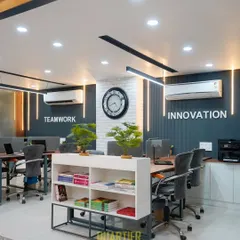 A wide view of a modern CA office in Indirapuram. The open-plan layout encourages collaboration, while the distinct zones, separated by a low bookshelf, maintain order. The combination of dark accent walls, bright lighting, and greenery creates a balanced and productive atmosphere.