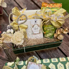 This wedding hamper, designed for Believe Weddings, showcases a modern Indian aesthetic with a green velvet tray and gold accents. It combines traditional snacks with elegant packaging and floral details for a sophisticated look.
