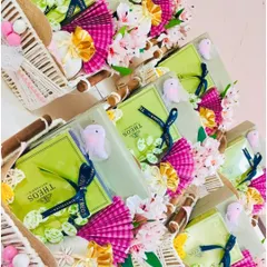 A collection of vibrant and festive baby shower return favors. These woven baskets are filled with goodies and decorated with bright pink and green floral details, creating a cheerful and celebratory gift for guests.