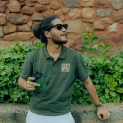 A casual portrait featuring a Royal Enfield polo shirt. The natural greenery and relaxed pose help create an authentic lifestyle feel, showing how the apparel fits into everyday moments.