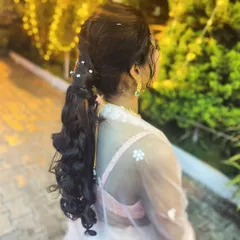 A stylish and modern ponytail with curls and pearl accents, perfect for a sangeet or cocktail party.