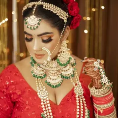 A perfect example of a classic bridal portrait. The model wears a red lehenga with our heavy green-beaded Kundan jewellery, complete with a nath, matha patti, and hath phool.