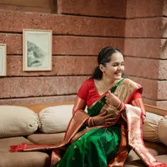 A candid shot of the bride-to-be, her face lit up with a happy smile, showcasing the elegance of her traditional attire in a comfortable home setting.