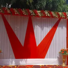 I can create bold graphic designs with fabric. This backdrop features a crown-like pattern made with red fabric against a white pleated curtain, topped with a red and white floral border.