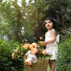Bubbles and flowers in the garden. This toddler looks up in wonder, creating a dreamy and enchanting outdoor portrait.