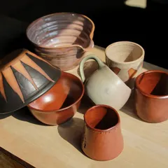 A dynamic group of student works, including a large mixing bowl and pieces with bold, graphic patterns applied with underglaze.