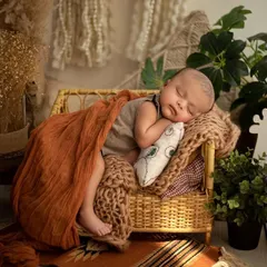 And just like that, he's fast asleep. This shows a classic newborn pose on a miniature sofa prop, surrounded by gentle, natural elements in my studio.