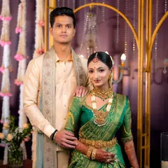 A full portrait of the bride and groom, showcasing their coordinated traditional attire. My makeup for the bride complements her green Kanjeevaram, while the groom’s makeup is natural and enhances his features.