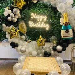 This birthday backdrop is all about celebration. It includes a balloon ring with star and champagne bottle foil balloons, all centered around a "Happy Birthday" neon sign, creating a fun and festive corner for photos.