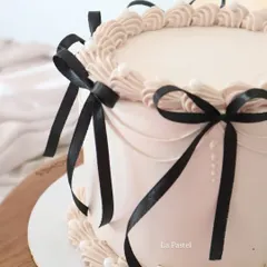 A chic and elegant cake with delicate piping and black satin bows. The contrast between the soft beige frosting and the bold black ribbons is so sophisticated.