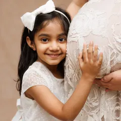 The pure joy of a big sister listening to her new sibling. This close-up shot captures the heartwarming connection and excitement that a new baby brings to the family.