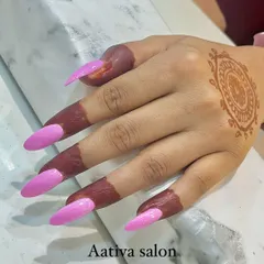 A popular combination for festive seasons is pairing mehendi with fresh nail art. This image shows a simple mandala mehendi on the back of the hand, perfectly complemented by long, bright pink stiletto nail extensions.