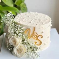 Minimal but make it luxe. This single-tier cake is perfect for soft launches and "just said yes" moments, adorned with fresh baby's breath, white roses, and a custom gold initial topper.