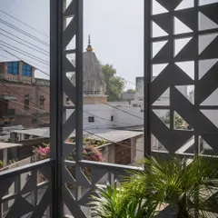 The facade's cast-concrete screen, assembled like Tetris blocks, mediates light, airflow, and privacy. This close-up shows how the geometric pattern frames a view of a nearby temple, connecting the home to its urban markers.