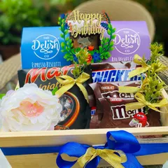 A close-up of the birthday hamper, showing the custom 'Happy Birthday' cake topper nestled among gourmet cookies and a variety of popular chocolates.