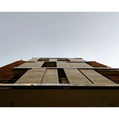 A view looking up at the facade, showing how the perforated screens create a dynamic and functional exterior. These shading devices are crucial for managing heat gain from the sun, which is a core principle of energy-efficient building design.