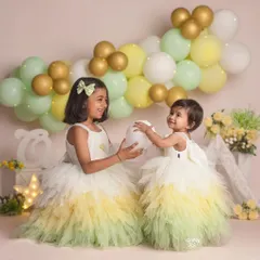Another angle of these two sisters playing together. Their bright dresses and the cheerful balloon backdrop create a light and joyful atmosphere.