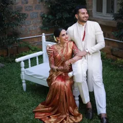 Classic and timeless. The groom’s crisp white kurta-pajama set, accented with a simple red detail, provides a clean, elegant contrast to the bride's traditional red and gold silk saree, proving that sometimes simplicity is the ultimate sophistication.