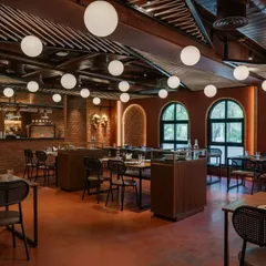 This view of 'Chambal' shows the bar and seating arrangement. The layout is designed for efficient service flow, while the mix of globe lights, arched windows, and wood furniture provides a rustic yet elegant ambiance.