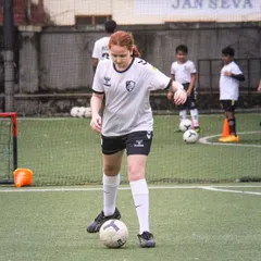 A player from our girls' batch stands poised over the ball, ready to execute a drill with the determination and focus we instill in all our athletes.