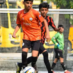 A young player focused on controlling the ball while being marked by an opponent. This demonstrates the composure and close control we develop in our athletes.