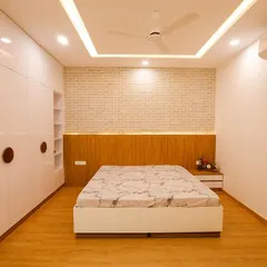 A clean and modern bedroom featuring a white brick accent wall and a floating wooden headboard with backlighting. The full-wall wardrobe provides extensive storage, keeping the room feeling spacious and uncluttered.