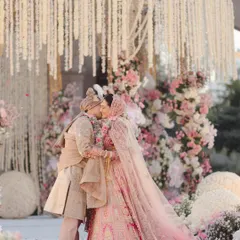 A kiss that seals their forever, surrounded by a cloud of pastel florals. I designed this mandap with cascading white flowers and soft pink roses to create a truly romantic and dreamy setting for their vows.