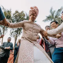 The groom being playfully pulled onto the dance floor by his family. These are the energetic, candid moments that show the joy of the celebration.
