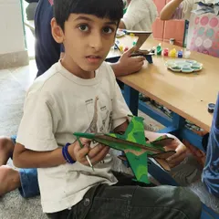 A young creator puts the finishing touches on his camouflage-themed fighter jet. This activity helps develop fine motor skills and attention to detail.