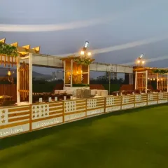 An outdoor lawn setup offers a unique charm for evening events. This is the dining area on the lawn at Ellora Banquet hall in Sanpada, featuring a modern wooden pergola design and elegant buffet counters.