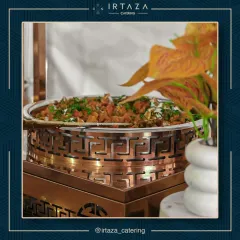 A close-up of a delicious vegetable dish served in an ornate copper and rose gold chafing dish. The fresh garnish and beautiful serveware show that even main courses are presented with artistic flair.