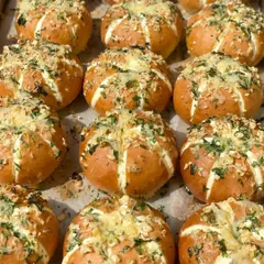 Freshly baked Korean Cream Cheese Buns, straight out of the oven. The tops are golden brown and covered in garlic and herbs.