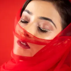 A dramatic and artistic shot featuring a glitter liner. Using props like this red veil can add a whole new dimension to a makeup photoshoot.