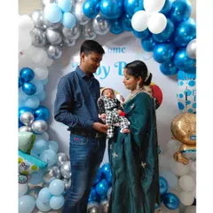 The proud parents with their newborn in front of the welcome home decor. The blue, white, and silver color scheme is a classic choice for celebrating a baby boy.