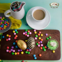 Indulge in our rich, dark chocolate Easter eggs. This image displays our beautifully crafted eggs, including a golden egg and one with a marbled design, surrounded by colorful candies.