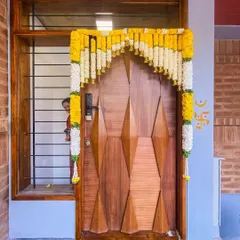 The entrance to the Tripathy home, adorned for the housewarming. The custom wooden door provides a warm welcome, contrasting beautifully with the earthy brickwork.