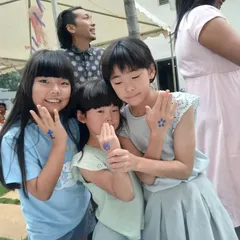 Friends showing off their matching blue glitter tattoos together. Getting body art is a fun group activity that adds a special, memorable touch to any celebration.
