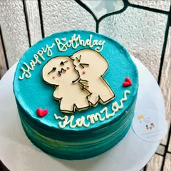 A custom cake with a cute and quirky illustration of a couple kissing. The ombre blue-green background adds a beautiful, artistic touch to this birthday cake.
