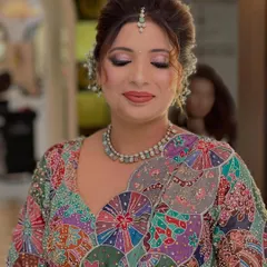 A beautiful party look featuring a colorful, artistic blouse. The makeup is soft and glamorous, with shimmery lilac eyeshadow and a matching lip color.
