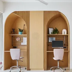 We designed this shared study area with two arched nooks, giving each sister her own dedicated workspace. A central cabinet provides storage, and the light wood and soft pink chairs keep the space feeling bright and cheerful.