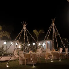 We create magical atmospheres like this "dining under the stars" experience for a milestone birthday. The fairy-lit teepee structures provide an intimate and whimsical setting for guests, perfect for garden parties and boho-themed soirées.
