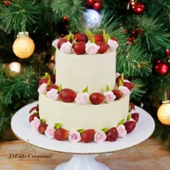 A beautiful two-tier cake decorated with fresh strawberries and delicate pink sugar roses, perfect for a festive or romantic occasion.