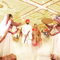 This wide-angle shot captures the scale and drama of the couple's entrance, complete with dancers and theatrical smoke. It shows the full grandeur of the wedding celebration.