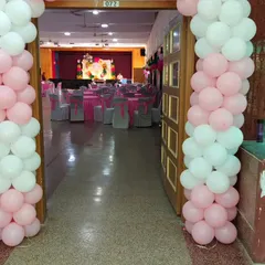 The entrance to the hall for the christening party, decorated with pink and white balloon pillars, giving guests a peek at the main stage inside.