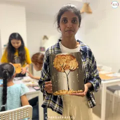 A participant displays her beautiful gold foil tree painting, a unique piece created in one of our specialty workshops.